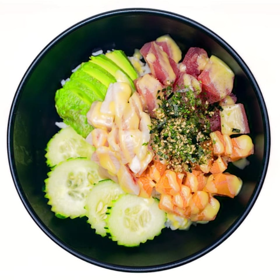 A Twin Sushi PDX poke bowl with tuna, salmon, avocado, cucumber, and seaweed flakes.