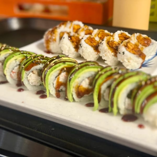 Two plates of Twin Sushi PDX rolls, one with avocado and sauce, the other with eel sauce.