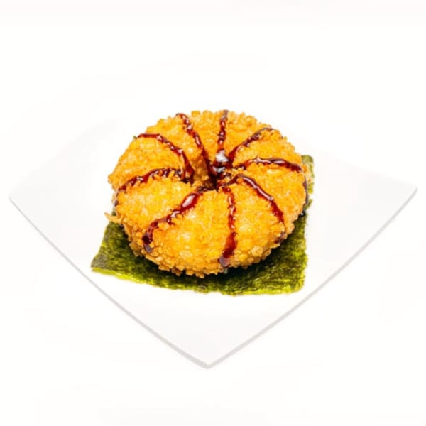 Deep-fried sushi donut drizzled with dark sauce, served on a nori sheet and white plate.